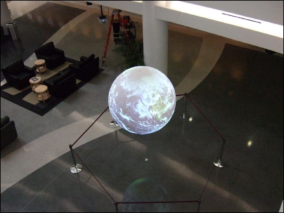 Viewed from above, the black hole is slightly visible as a black diamond at the top of the sphere. The black hole is less pronounced due to a high degree of ambient light in the lobby