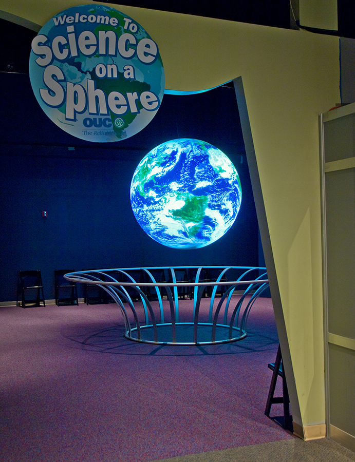 A single metal ring held up by curved metal posts that bend outward keeps visitors from reaching Science On a Sphere at the Orlando Science Center