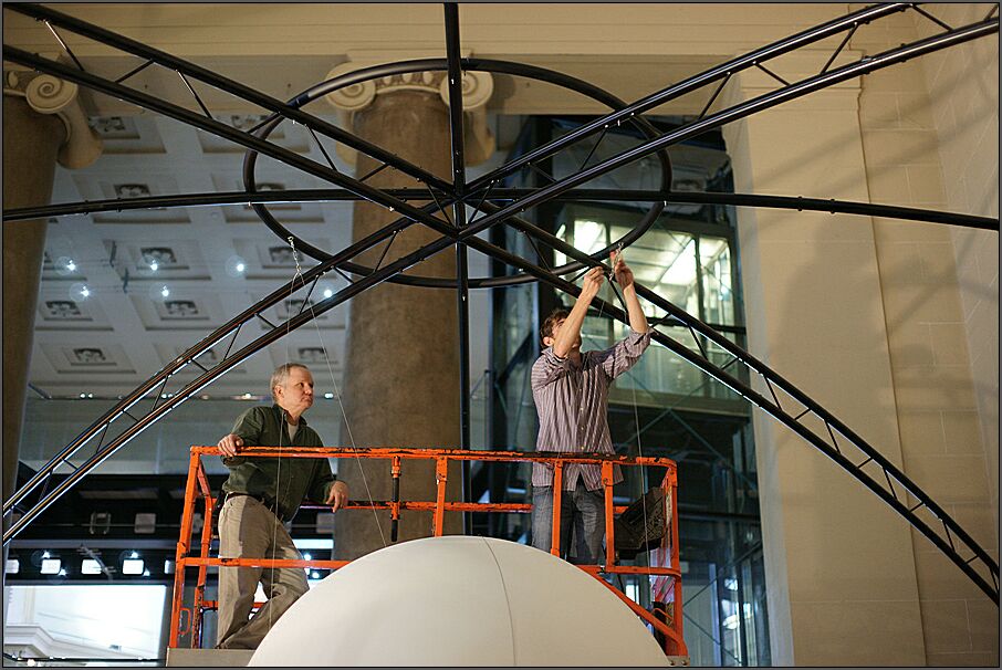 A free-standing frame made of curved metal rods is used to hang Science On a Sphere. The Sphere is attached to a metal circle at the top of the domed frame
