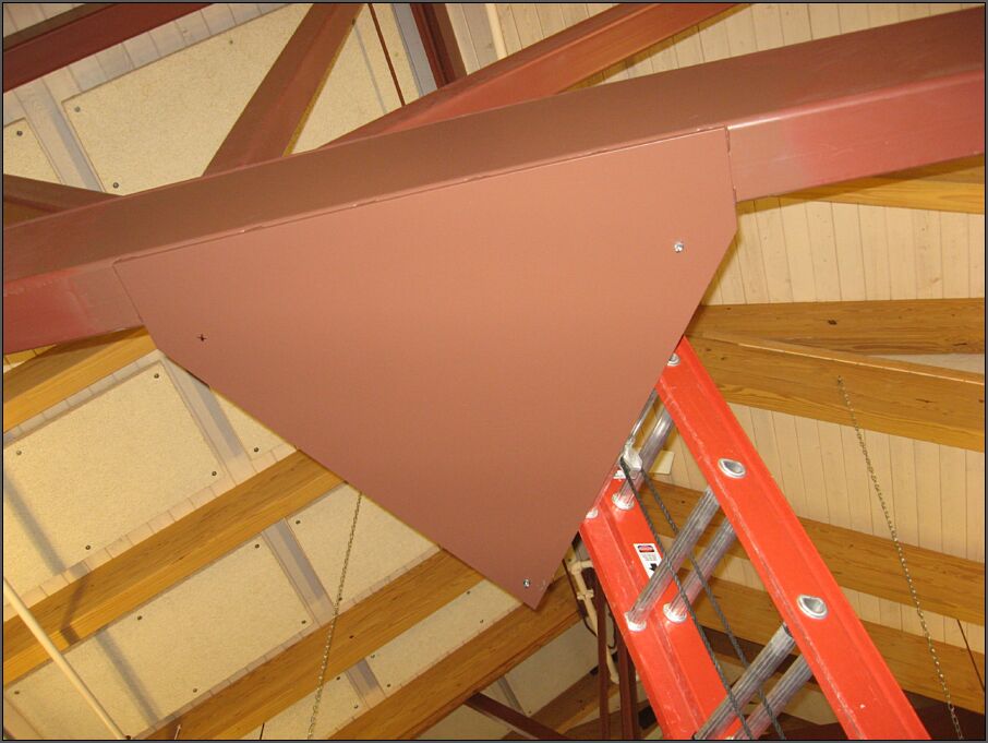 A solid metal plate attached to a metal cross-beam in the ceiling that has three holes drilled at the corners of an equilateral triangle where Science On a Sphere's support wires will be attached