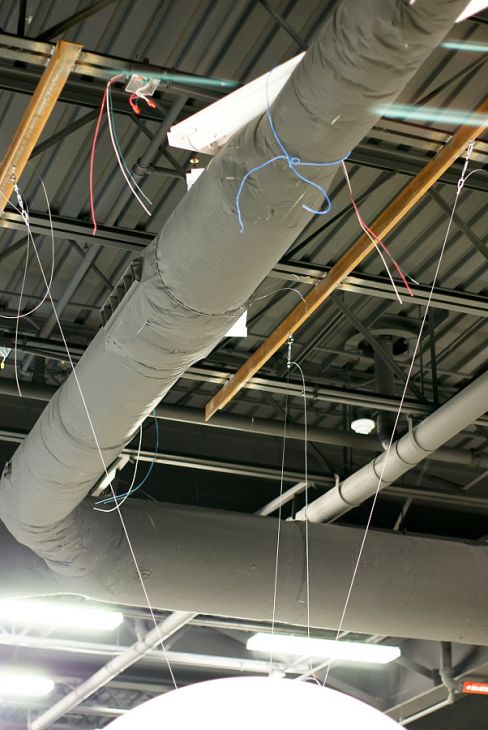 Three wires that support Science On a Sphere are mounted into two metal angle brackets that are attached to the metal frame of a ceiling